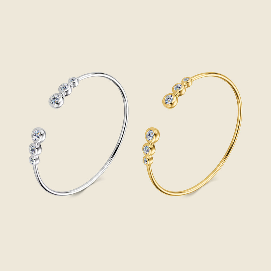 The Bezel Cuff in silver and in gold plated, side by side on a cream ground.