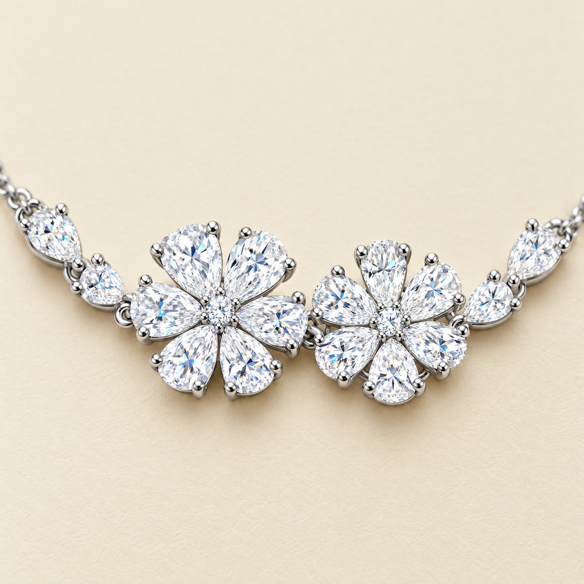 Close view of the two flowers, each petal a pear-cut stone held in prongs around a small round center, with small pear stones flanking each flower.