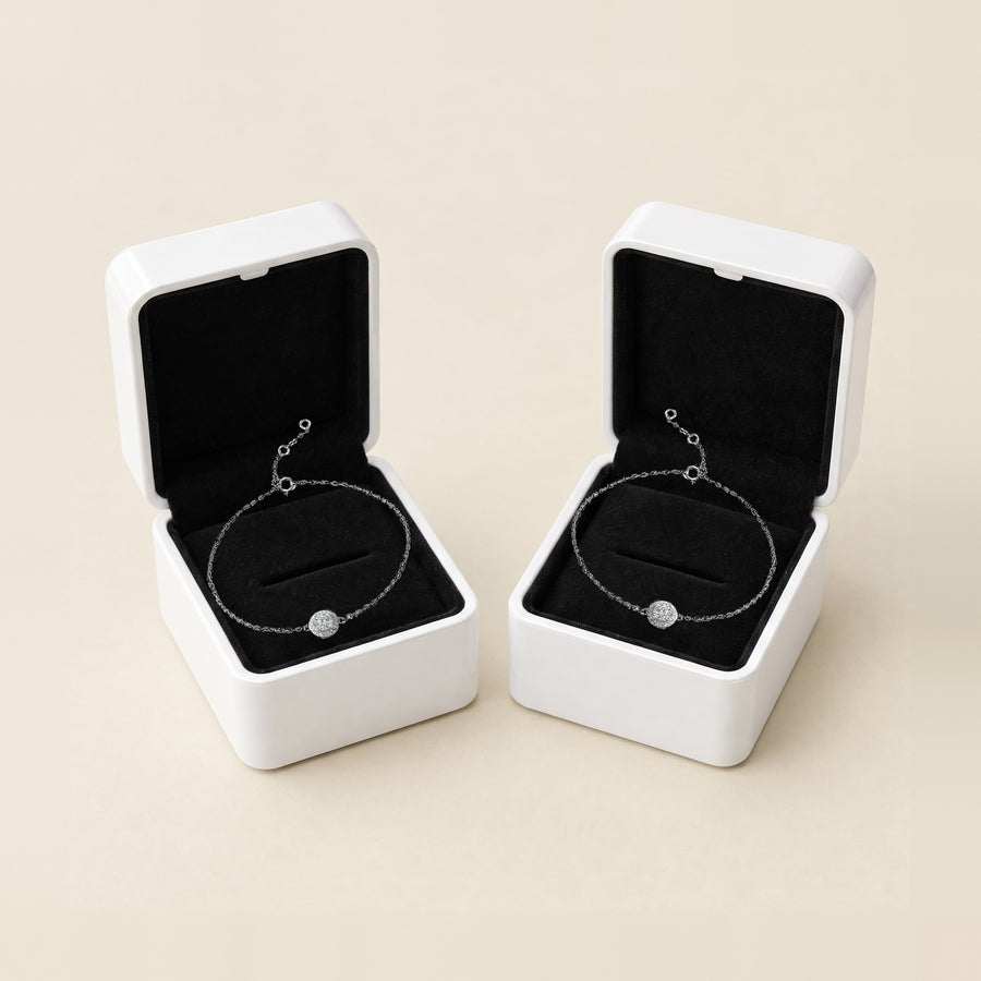 Two Halo bracelets side by side on a cream ground, each in its own open white box with a black velvet interior, both silver.