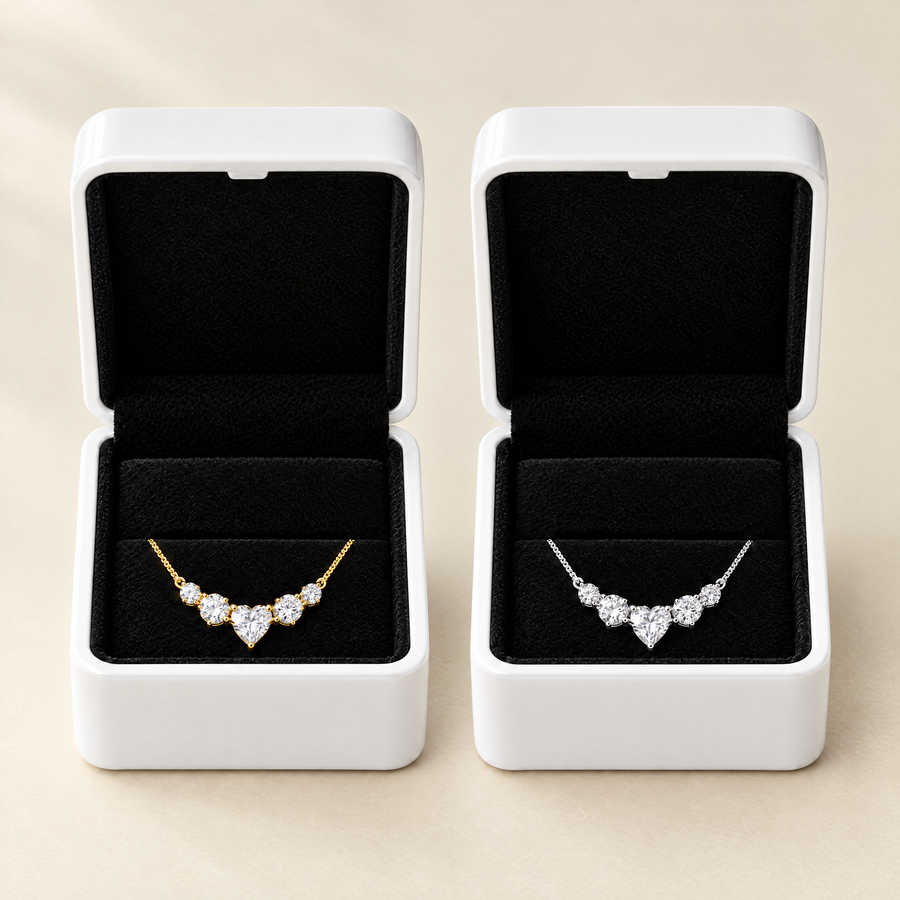 Two open white boxes side by side on a cream ground, black velvet inside each, one necklace gold plated and one silver.