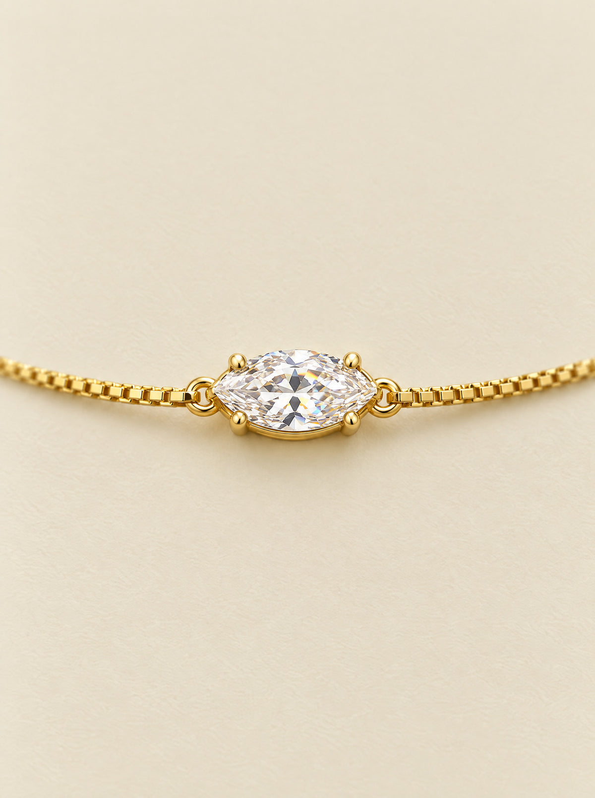 Close view of the marquise moissanite, its two points running along the chain, held in a four-prong basket on gold plated sterling silver.