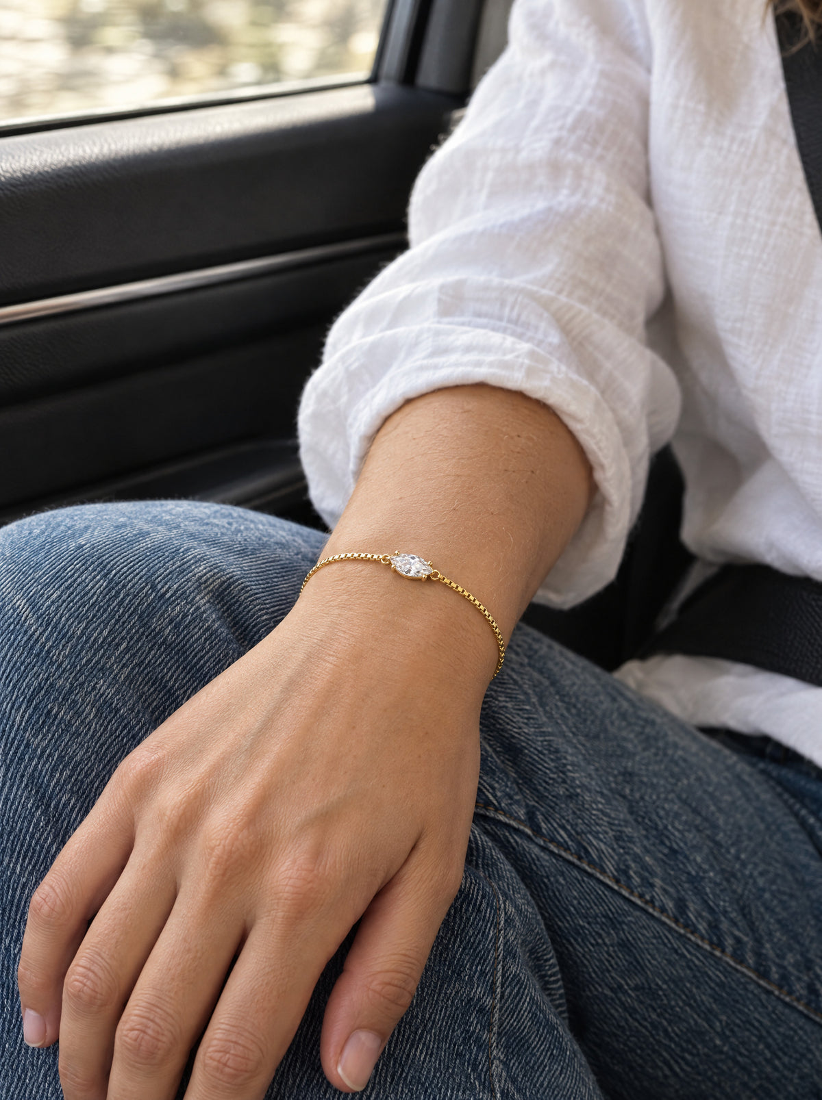 The bracelet worn on a woman's wrist in daylight, the marquise stone lying flat along the top of the wrist, the box chain fastened along the extension.