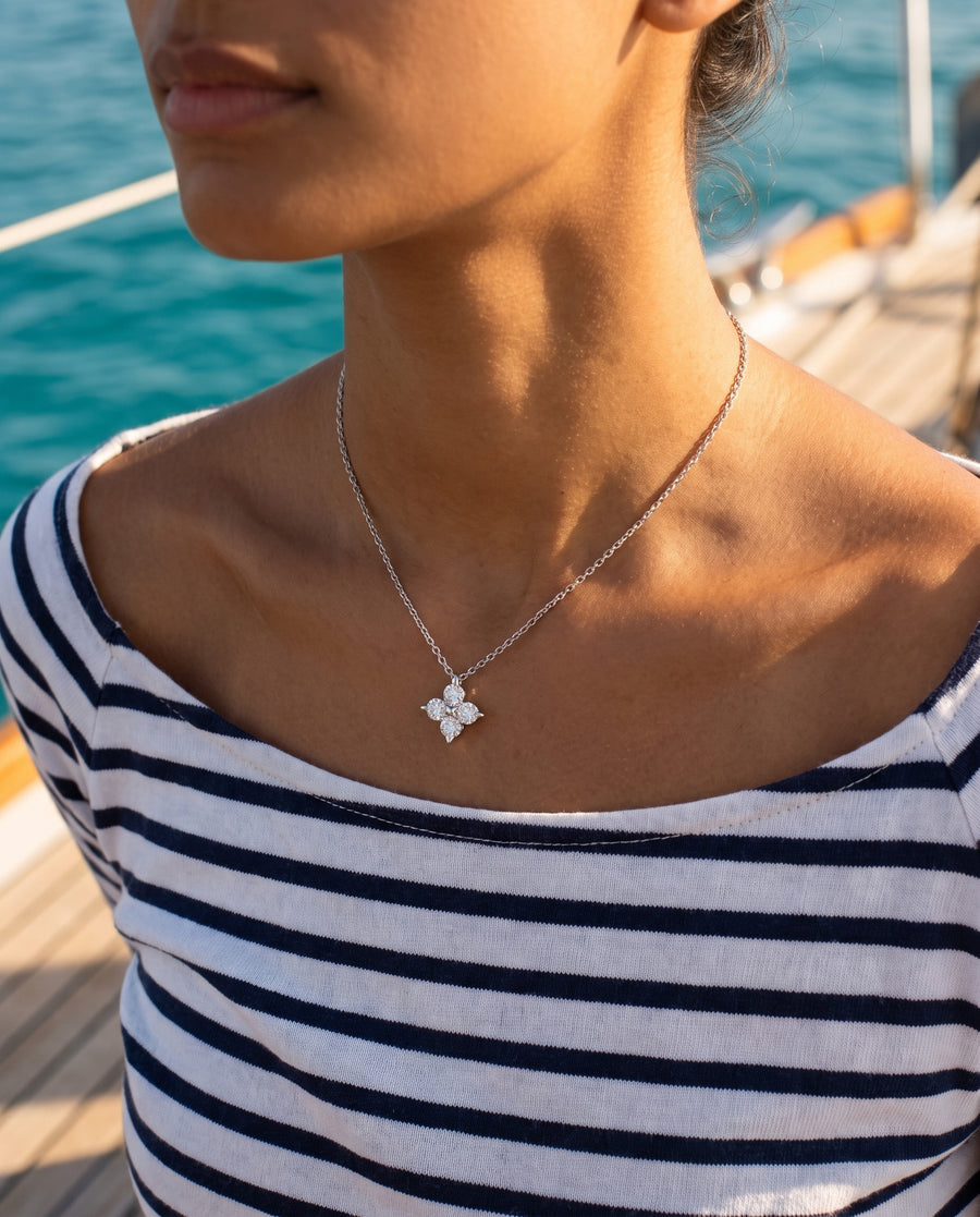 A boat deck in bright sun in an off-shoulder striped top, sea behind, cropped at the chin.