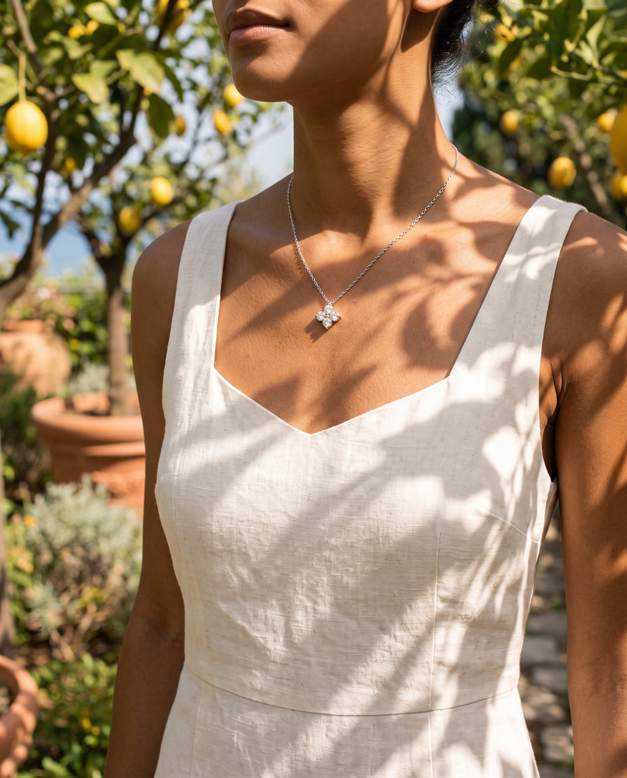 A lemon-garden walk in a linen sundress, warm sun and leaf shadows on her skin, cropped at the chin.