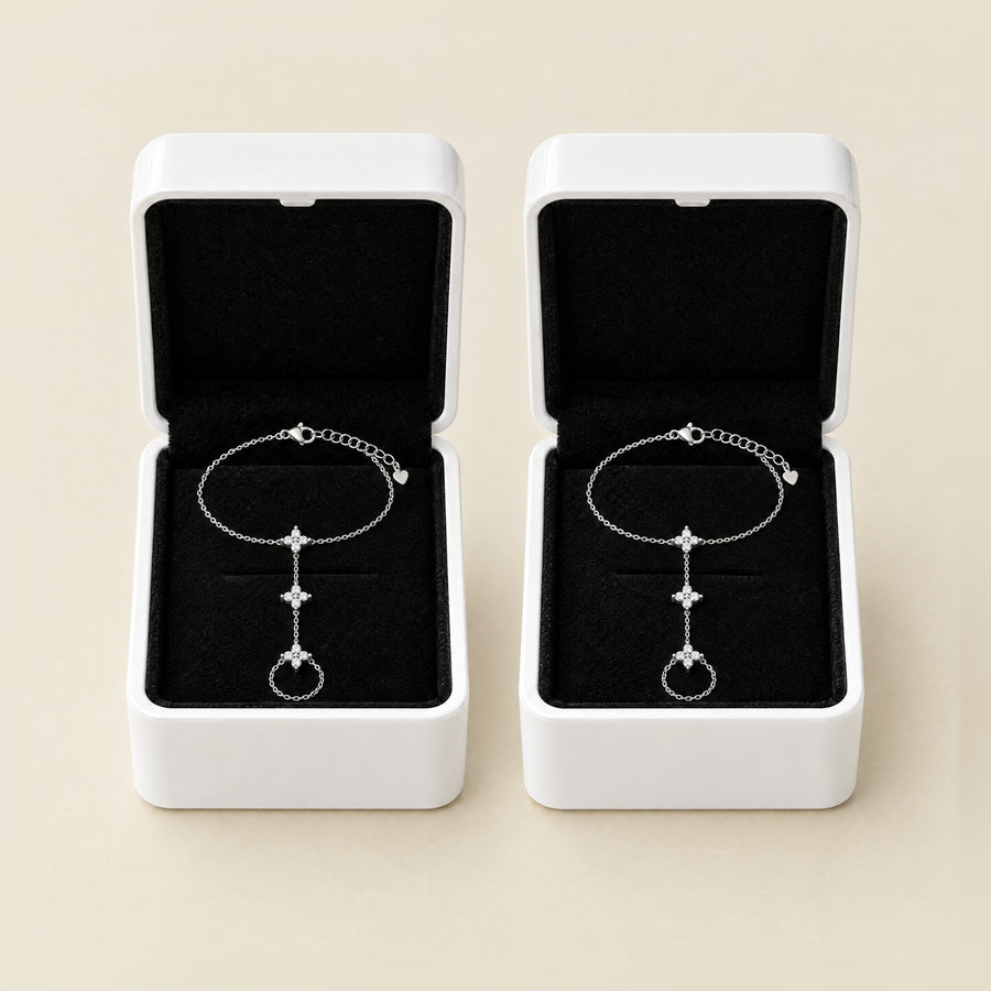Two star hand chains, each in its own open white box with a black velvet interior, side by side on cream.