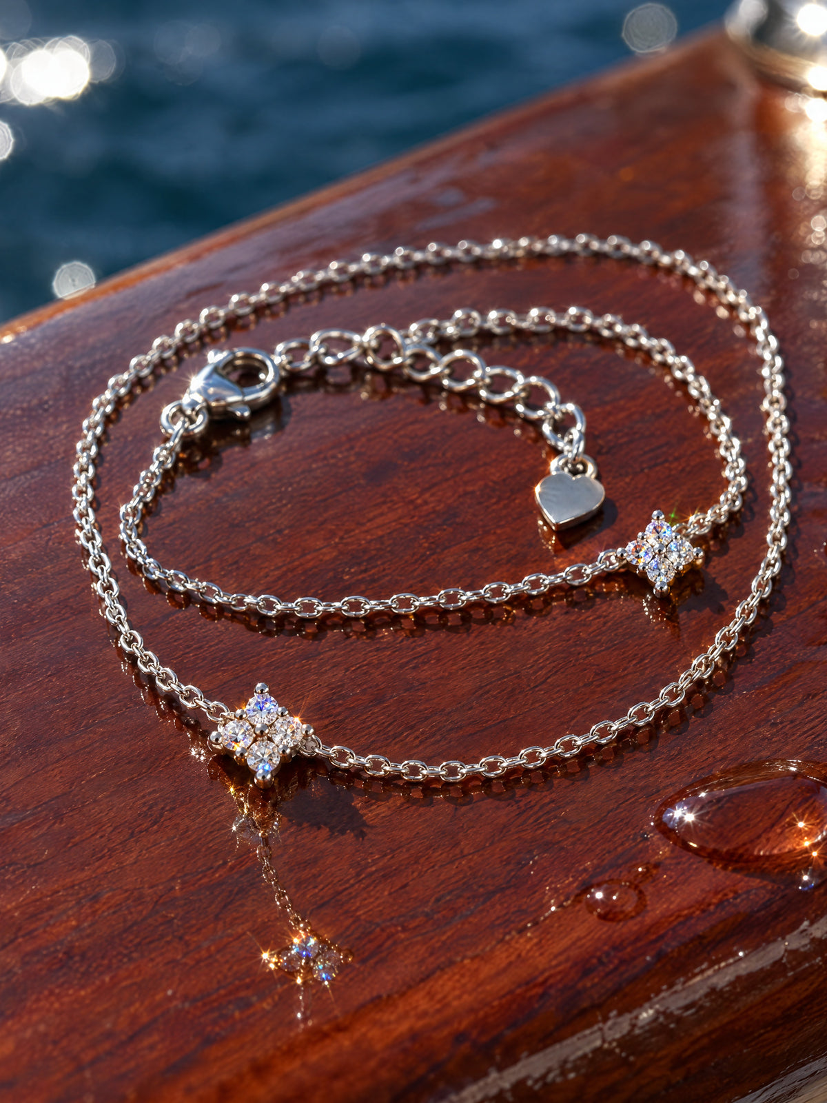 The Mossante Star Hand Chain on polished mahogany: the bracelet loop with its lobster clasp, extension chain and tiny heart tag, the connector chain and the four-stone stars.