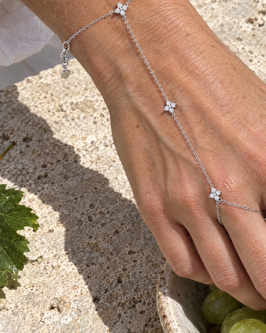 A woman's hand reaching for a bowl of figs on sunlit stone, the finger star closest to the lens.
