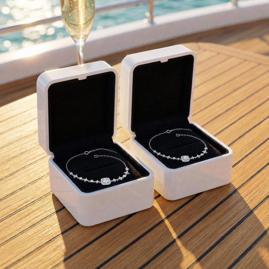 Two open white boxes with black velvet on a sunlit yacht table, a Starlight bracelet in each.