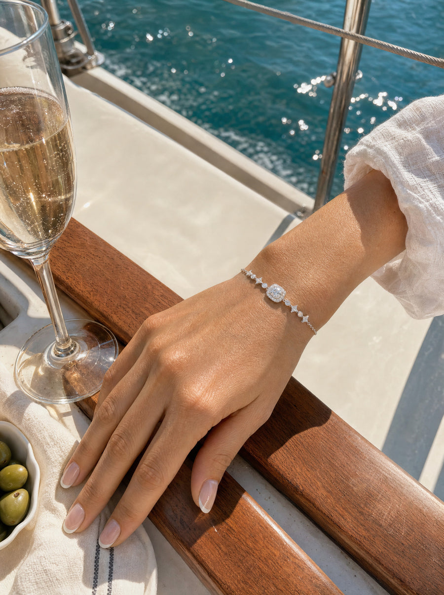 Her hand on the polished teak rail of a white yacht beside a champagne flute, the Starlight bracelet at her wrist.