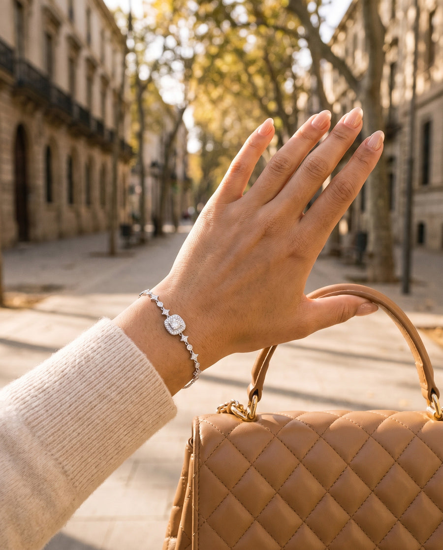 A sunny boulevard: her hand holding the top handle of a structured quilted leather designer bag (no logo).