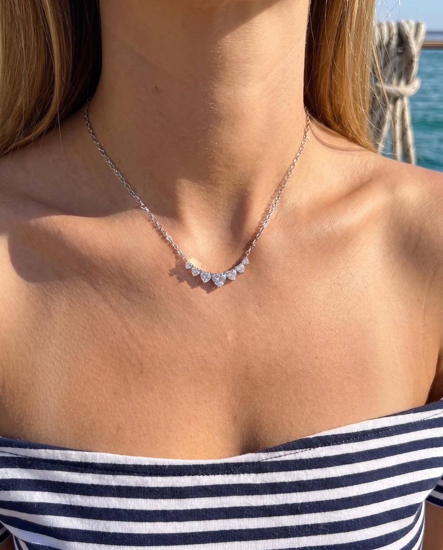 A boat deck in bright sun in an off-shoulder striped top, sea behind, cropped at the chin.