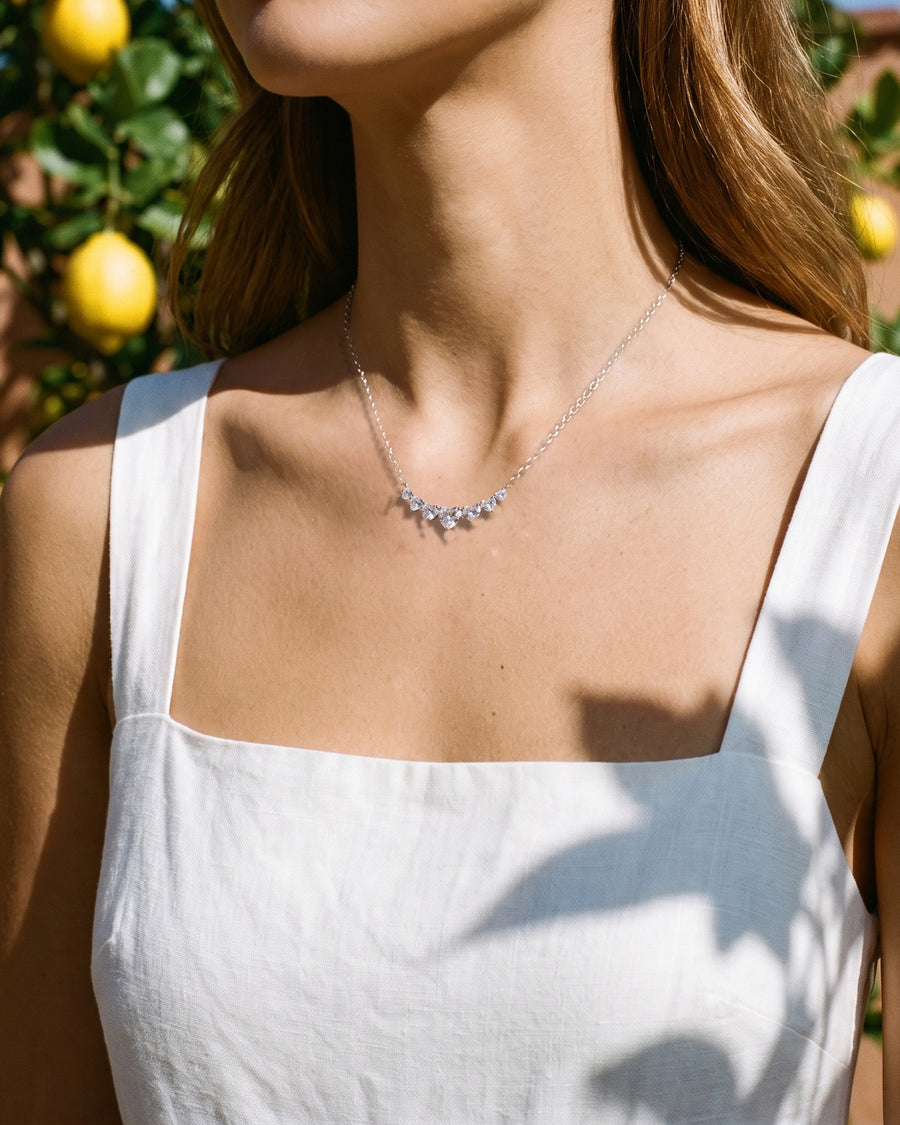 A lemon-garden walk in a linen sundress, warm sun and leaf shadows on her skin, cropped at the chin.