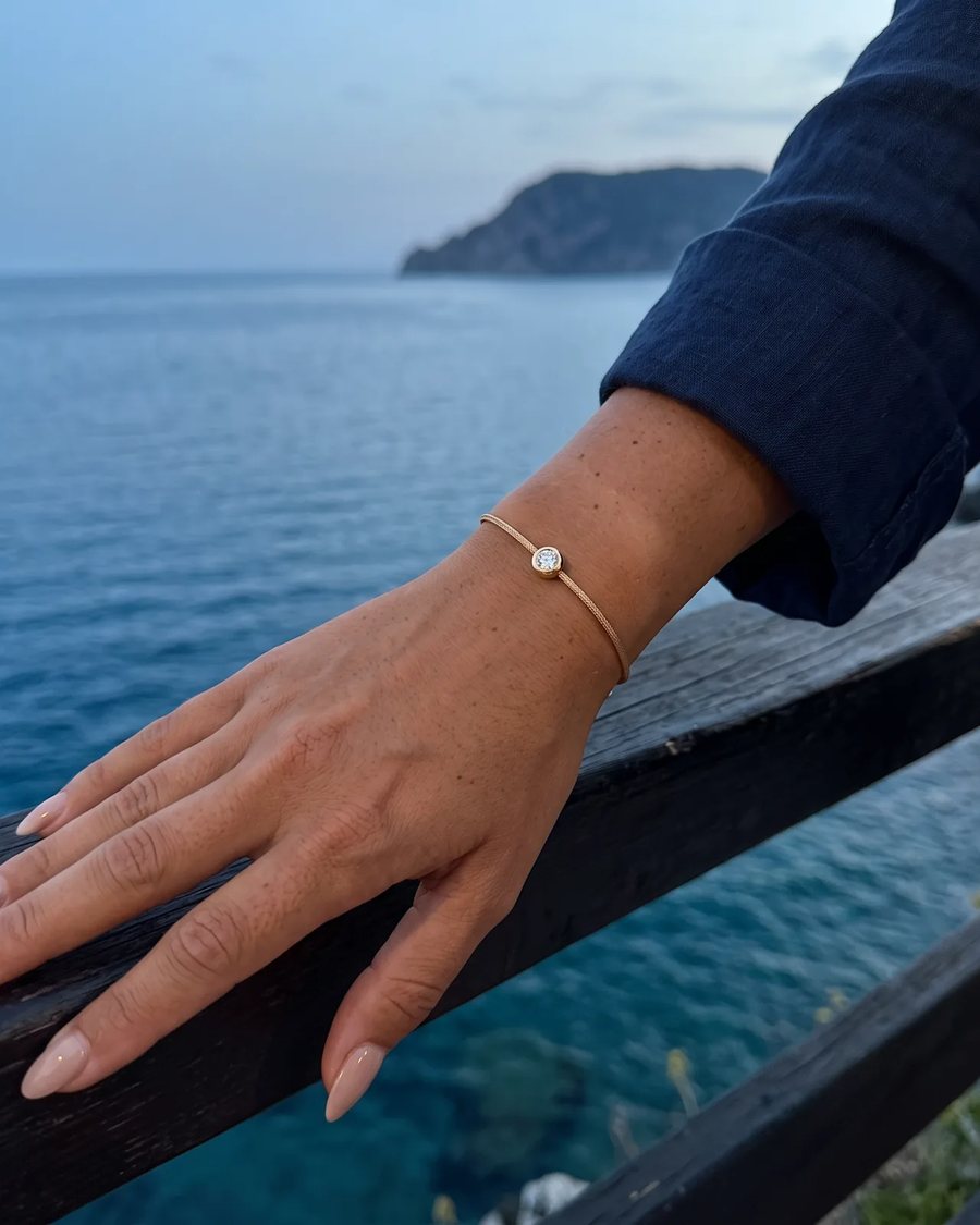The Gold bracelet worn at a railing above the sea