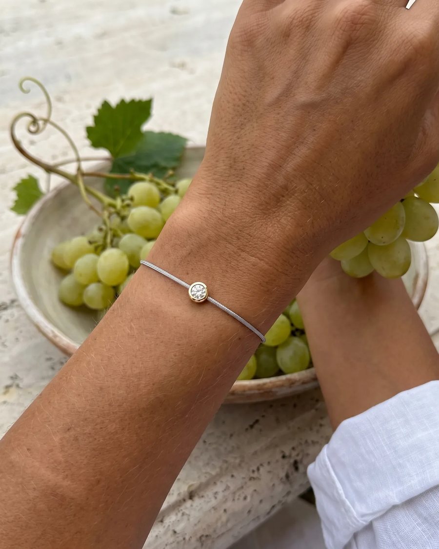 The Silver bracelet worn beside a bowl of grapes